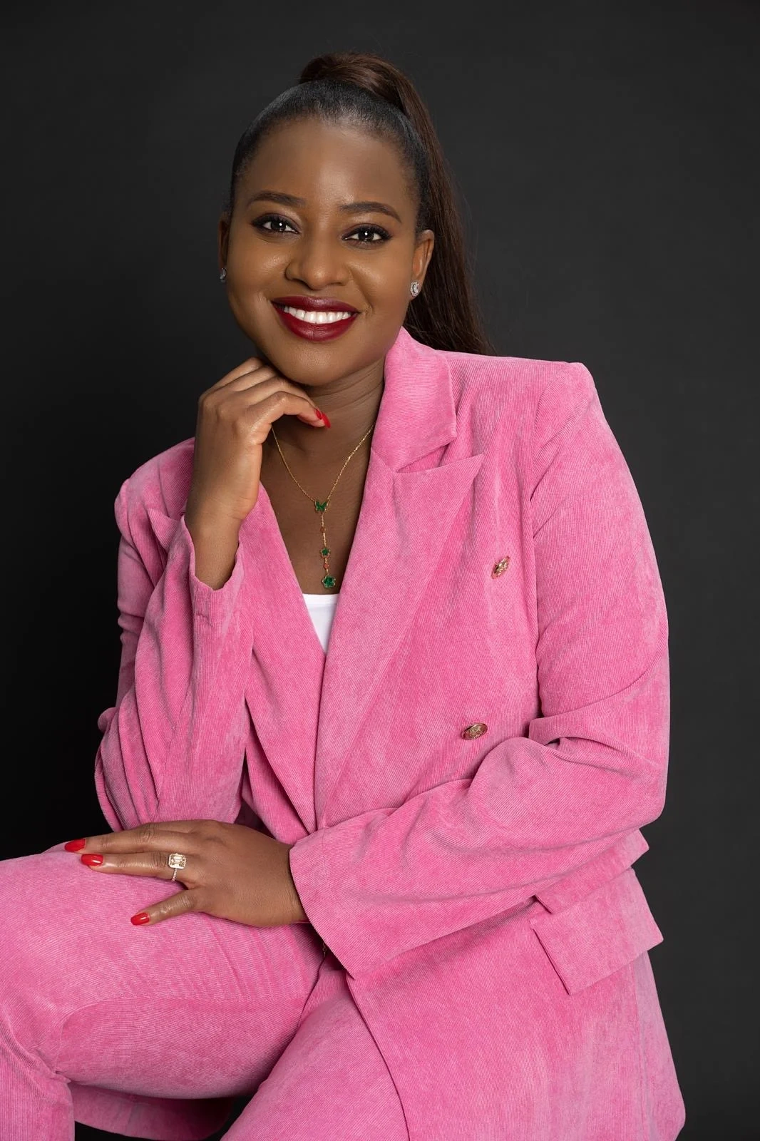 Mimi smiling in a pink tailored suit