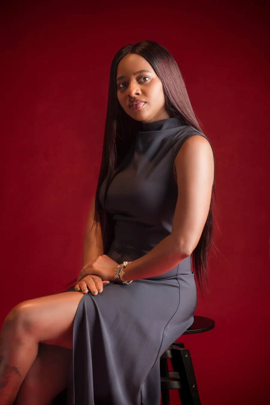Mimi in a charcoal dress against a red studio backdrop